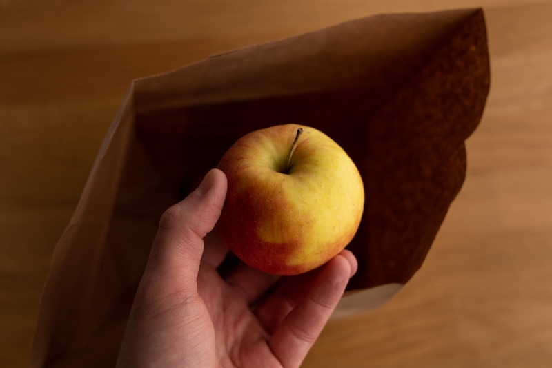 Adding an apple to a brown bag