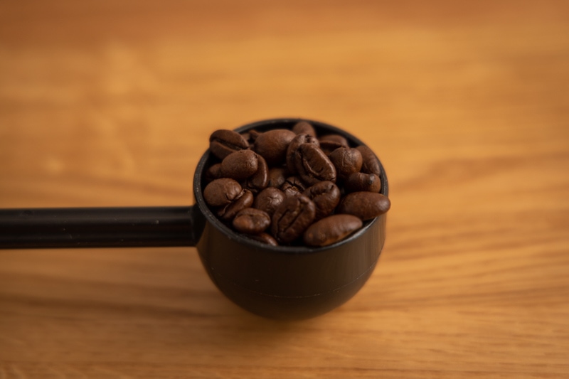 Coffee beans in a measuring spoon