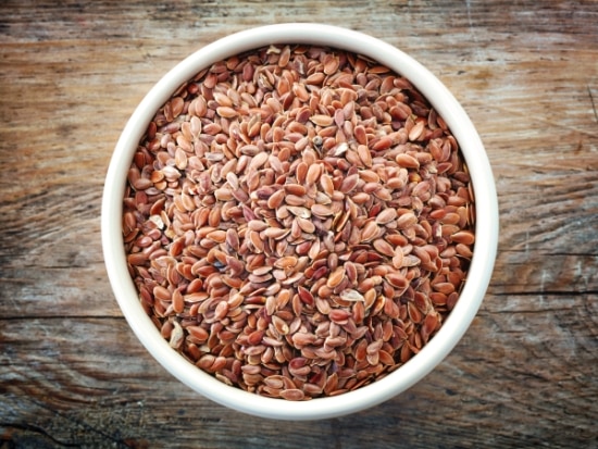 A bowl of flax seeds on a wooden table