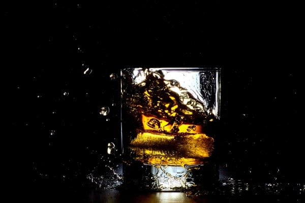 Ice falling into a glass of whiskey