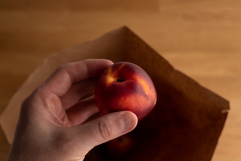 Placing nectarines in an brown bag to ripen