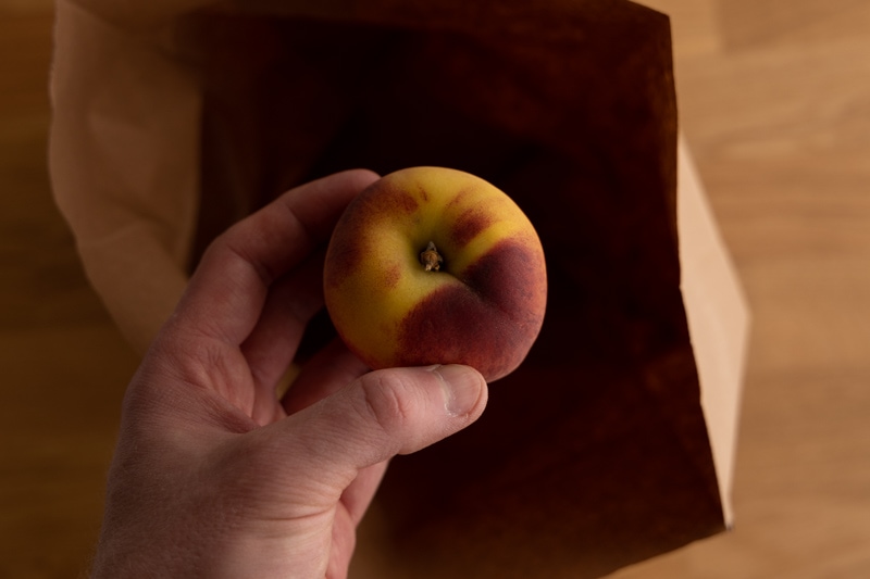 Placing a peach in a brown bag