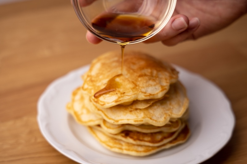 Pouring maple syrup over pancakes