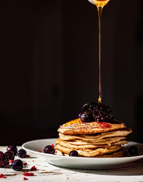 Pouring syrup over a pile of pancakes