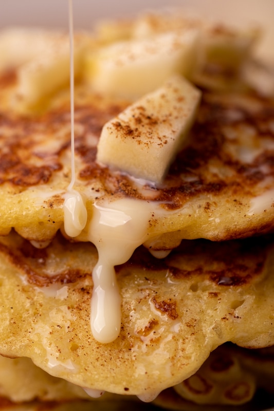 Pouring thawed condensed milk over a pile of pancakes