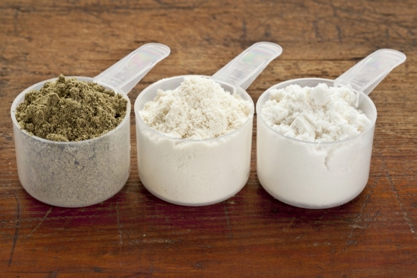 Scoops of three protein powders (from left hemp seed, whey concentrate, whey isolate)