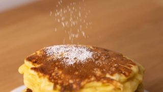 Sprinkling powdered sugar over pancakes