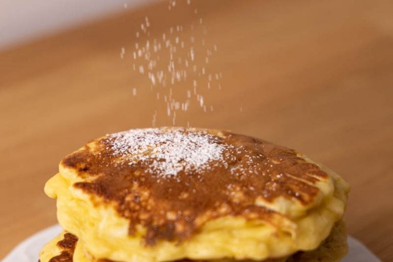 Sprinkling powdered sugar over pancakes