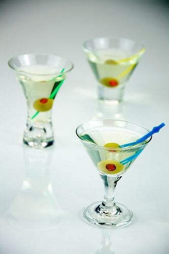 Three minature dirty martinis served with a traditional olive garnish