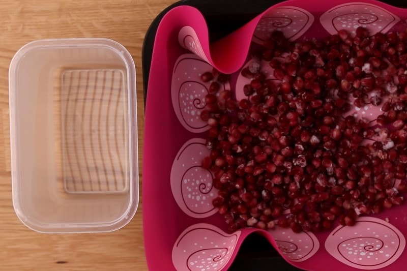 Transferring frozen pomegranate seeds to a container