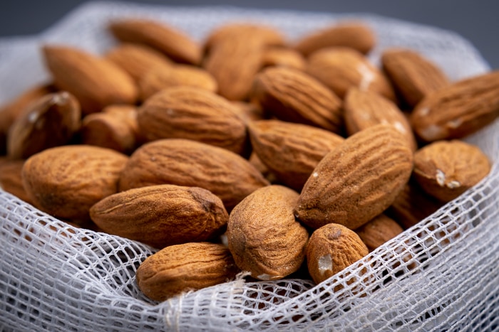 Unpeeled almonds in a mesh bag